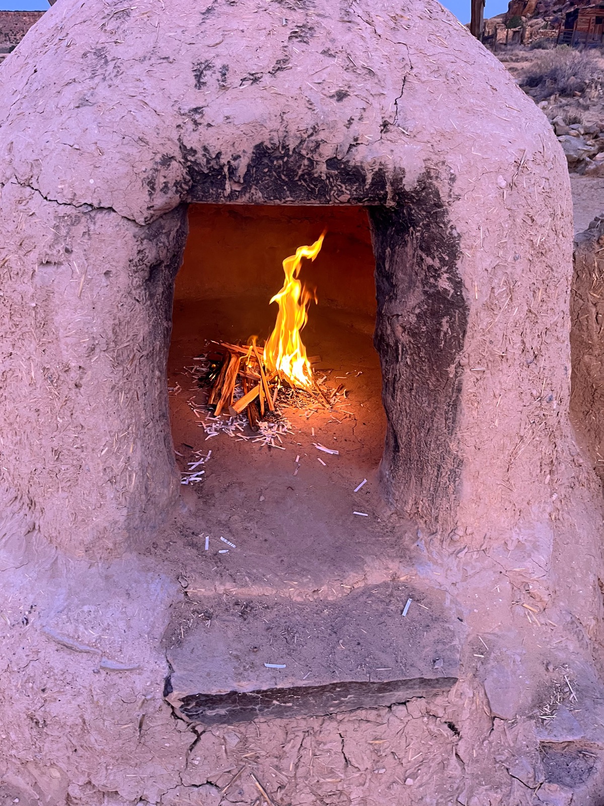 A fire burning inside an adobe horno oven