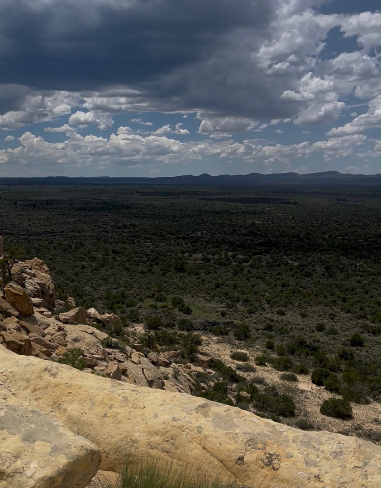 Clouds drifting over a juniper-covered valley below the mesa
